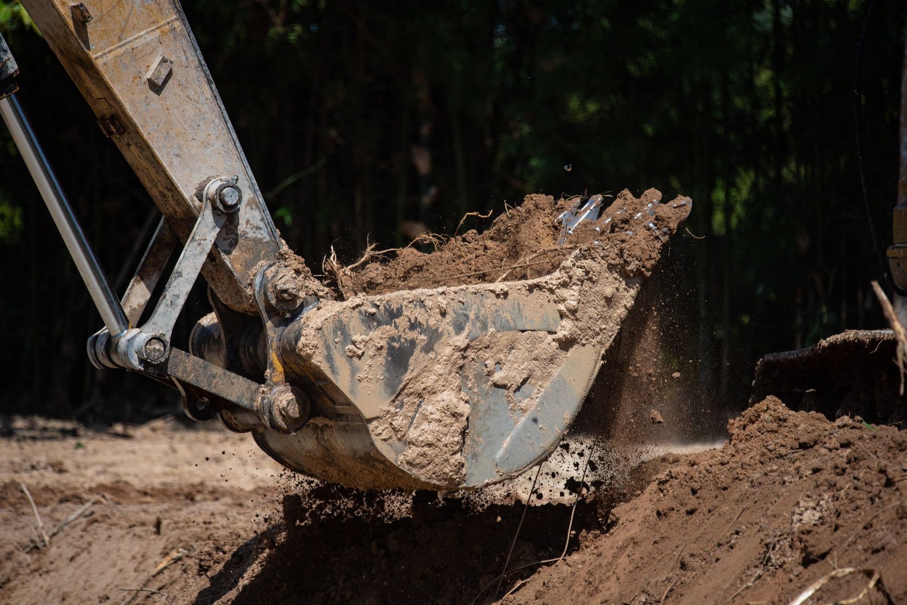 Excavator bucket digging soil for inspection